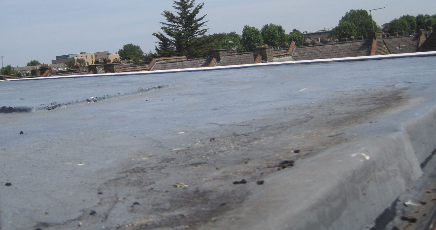 General view showing the extent of the GRP-covered flat roof areas, including visible staining and discolouration associated with ponding water. General view showing the extent of the GRP-covered flat roof areas, including visible staining and discolouration associated with ponding water.